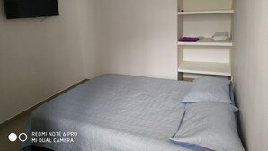 A bedroom with a bed, a TV mounted on the wall, and a white air conditioner. - cerca al centro y a la playa. Cerca a todo (cartagena)