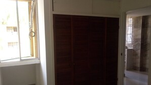 A room with a large wooden wardrobe, a window with blinds, and a tiled wall. - cerca al centro y a la playa. Cerca a todo (cartagena)