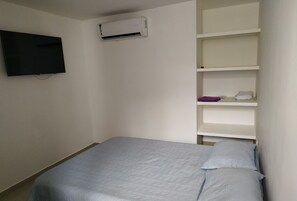 A bedroom with a bed, a TV mounted on the wall, and a white air conditioner. - cerca al centro y a la playa. Cerca a todo (cartagena)