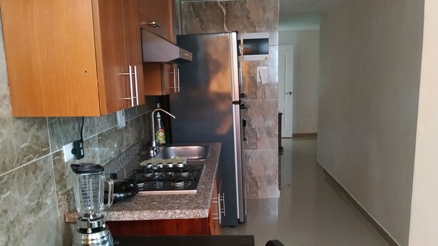 A modern kitchen with wooden cabinets, a gas stove, a blender, and a refrigerator. - cerca al centro y a la playa. Cerca a todo (cartagena)