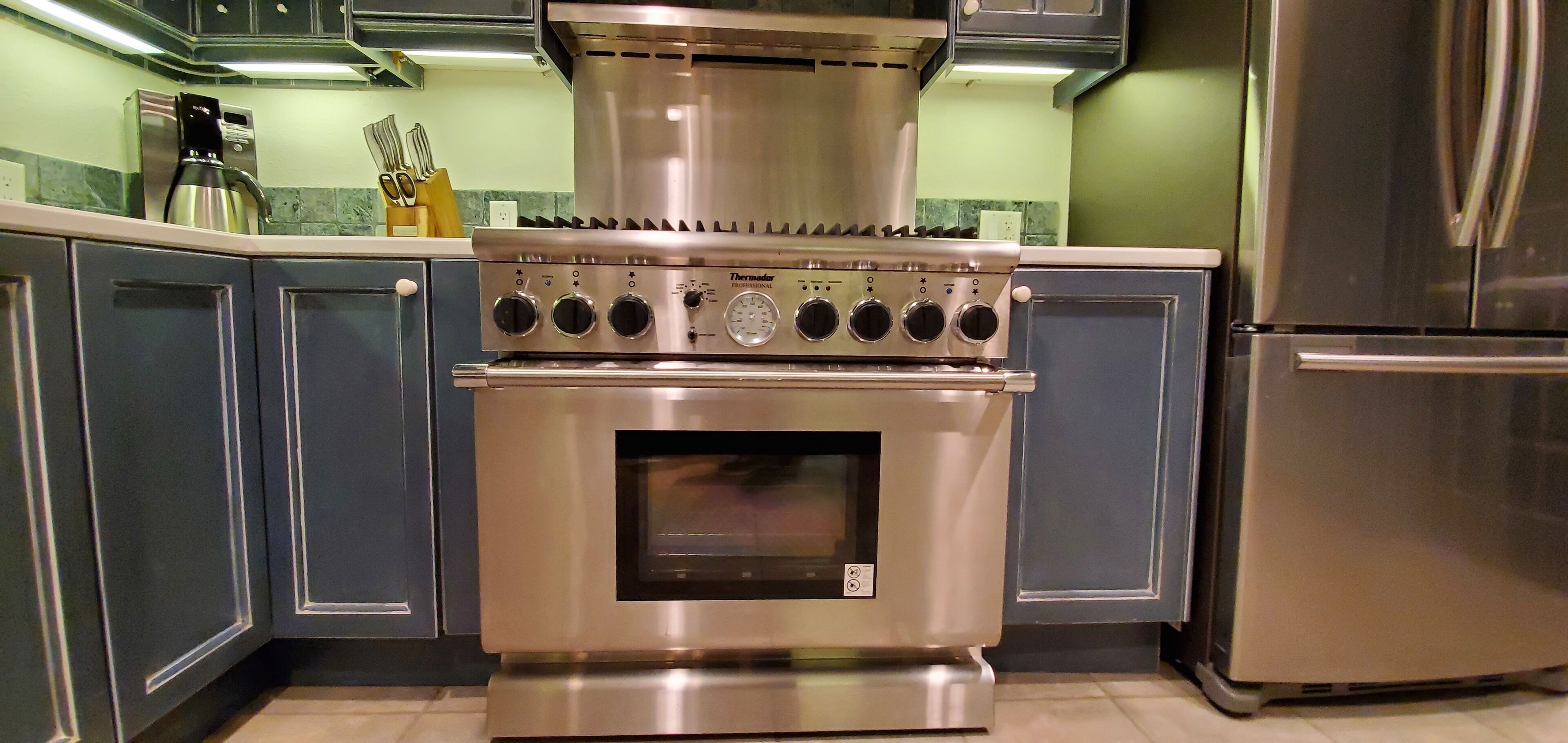 Une cuisine équipée d’une cuisinière professionnelle Thermador en acier inoxydable, d’un four encastré et d’un réfrigérateur en acier inoxydable.