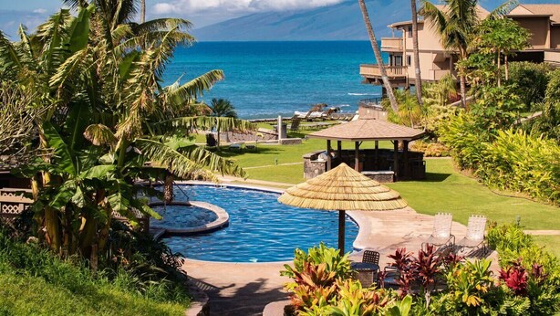A resort with a swimming pool, lounge chairs, and a view of the ocean.