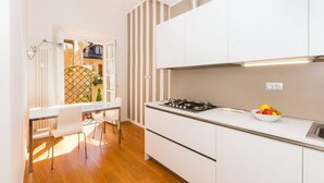 A modern kitchen with white cabinets, a gas stove, and a bowl of fruit on the counter.