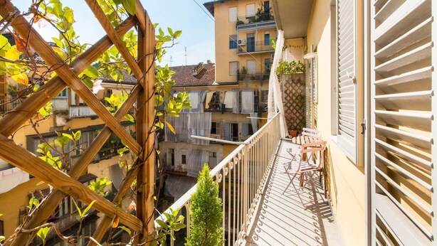 A balcony with a wooden trellis, a small table, and chairs.