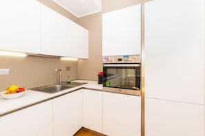 A modern kitchen with white cabinets, a stainless steel sink, and a built-in oven. - GuestHost - Roomy and elegant apartment equipped with every comfort for 6 people, located 600m from Porta Nuova railway and metro station and only 300m from Valentino Park. We are in the lively San Salvario district, symbol of Turin nightlife, in an area (Torino)