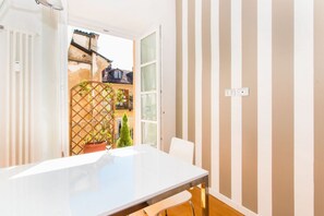 Une pièce avec une table blanche, une chaise, une fenêtre et une vue sur un jardin.