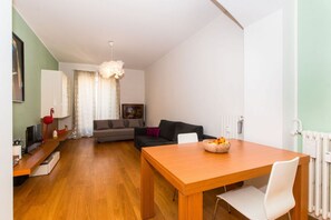 Ein modernes Wohnzimmer mit einem Holzesstisch, einem grauen Sofa, einem schwarzen Sofa und einer roten Flamingostatue.