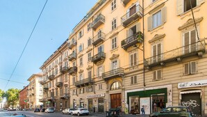 A multi-story building with balconies, a storefront labeled 'FERRAMENTA,' and a shop with a green awning.
