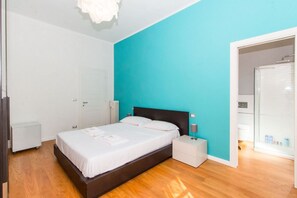 A modern bedroom with a large bed, bedside tables, a white wardrobe, and a bathroom with a shower. - GuestHost - Roomy and elegant apartment equipped with every comfort for 6 people, located 600m from Porta Nuova railway and metro station and only 300m from Valentino Park. We are in the lively San Salvario district, symbol of Turin nightlife, in an area (Torino)