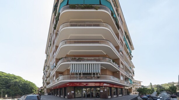 A multi-story hotel with balconies, a red awning, and a parked car in front. - GuestHost - Vatican Museums and St. Peter's Basilica! (Roma)