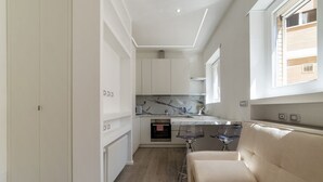 A compact kitchen with white cabinets, a marble backsplash, and a built-in oven. - GuestHost - Vatican Museums and St. Peter's Basilica! (Roma)