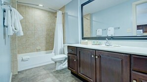 A bathroom with a bathtub, toilet, and a large mirror.