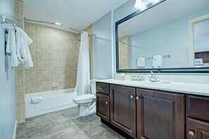 Un baño con bañera, inodoro y un espejo grande.