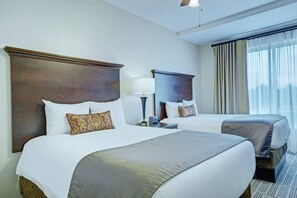 Habitación de hotel con dos camas, un ventanal grande con cortinas y un ventilador de techo.