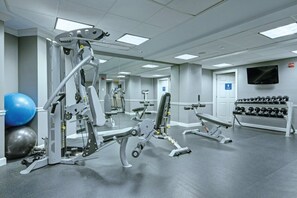 Un gimnasio con diversos equipos de ejercicio, incluyendo máquinas de pesas y mancuernas.