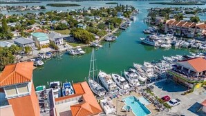 Un port de plaisance avec des bateaux amarrés, une piscine et des immeubles résidentiels aux toits rouges.