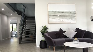A modern living room with a grey sofa, a round coffee table, and a staircase leading to another level. - Seaforth Retreat (Seaforth)