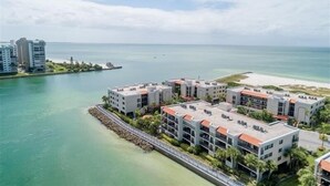 Un hotel frente al mar con varias construcciones, un puerto deportivo y una playa.