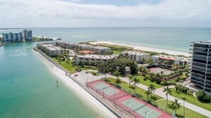 Zona residencial costera con edificios, una playa y una cancha de tenis.