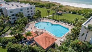 Un hotel con piscina rodeado de palmeras y vista al mar.