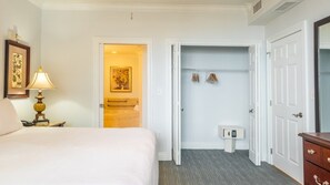 Una habitación de hotel con cama, lámpara, baño con lavamanos y espejo, y un armario.