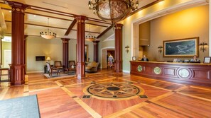 A lobby with a reception desk, wooden columns, a large globe, and a patterned floor.