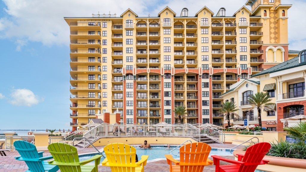 Un hôtel à plusieurs étages doté de balcons, d’une piscine et de chaises Adirondack aux couleurs vives.