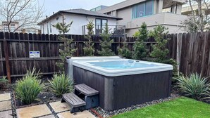 Een achtertuin met een jacuzzi, een pad van stenen en een houten omheining.