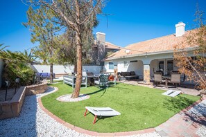 A backyard with a patio, outdoor furniture, and a well-maintained lawn. - Luxury by the strip 5 star home close to LVB and airport. Great family home. (Henderson)