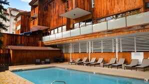 Un espace piscine équipé de chaises longues, d’un escalier pour accéder à la piscine et d’un panneau indiquant les règles à respecter.