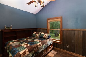 Un dormitorio con una cama grande, cabecera de madera y ventana con vistas a árboles.