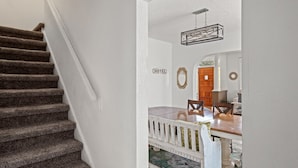 A staircase leading to a dining area with a wooden table and chairs, a hanging light fixture, and a 'HOTEL' sign on the wall. - 3 story home near downtown El Paso  (El Paso)