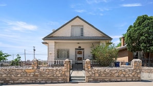 A single-story house with a gabled roof, a stone wall in front, and a metal gate. - 3 story home near downtown El Paso  (El Paso)