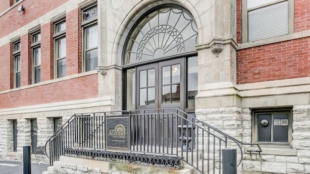 A building with a stone facade, a large arched window, and a metal staircase leading to a door labeled "Academy." - Historic Condo in the Heart of Mount Adams (Cincinnati)