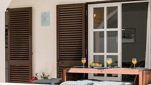 A poolside area with a table set for two, a window with blinds, and a view of the pool. - Sea La Vie Quintessential Algarve Villa with Pool in Manta Rota (Vila Nova de Cacela)