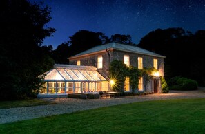 Ein großes, zweistöckiges Haus mit Wintergarten und gepflegtem Rasen.
