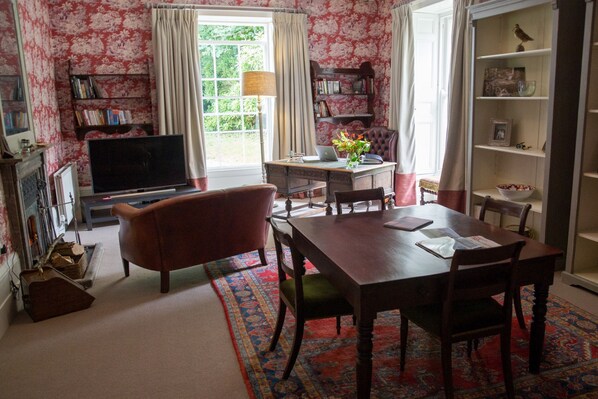 Ein traditionell eingerichtetes Wohnzimmer mit Kamin, Fernseher, Esstisch und Bücherregal.