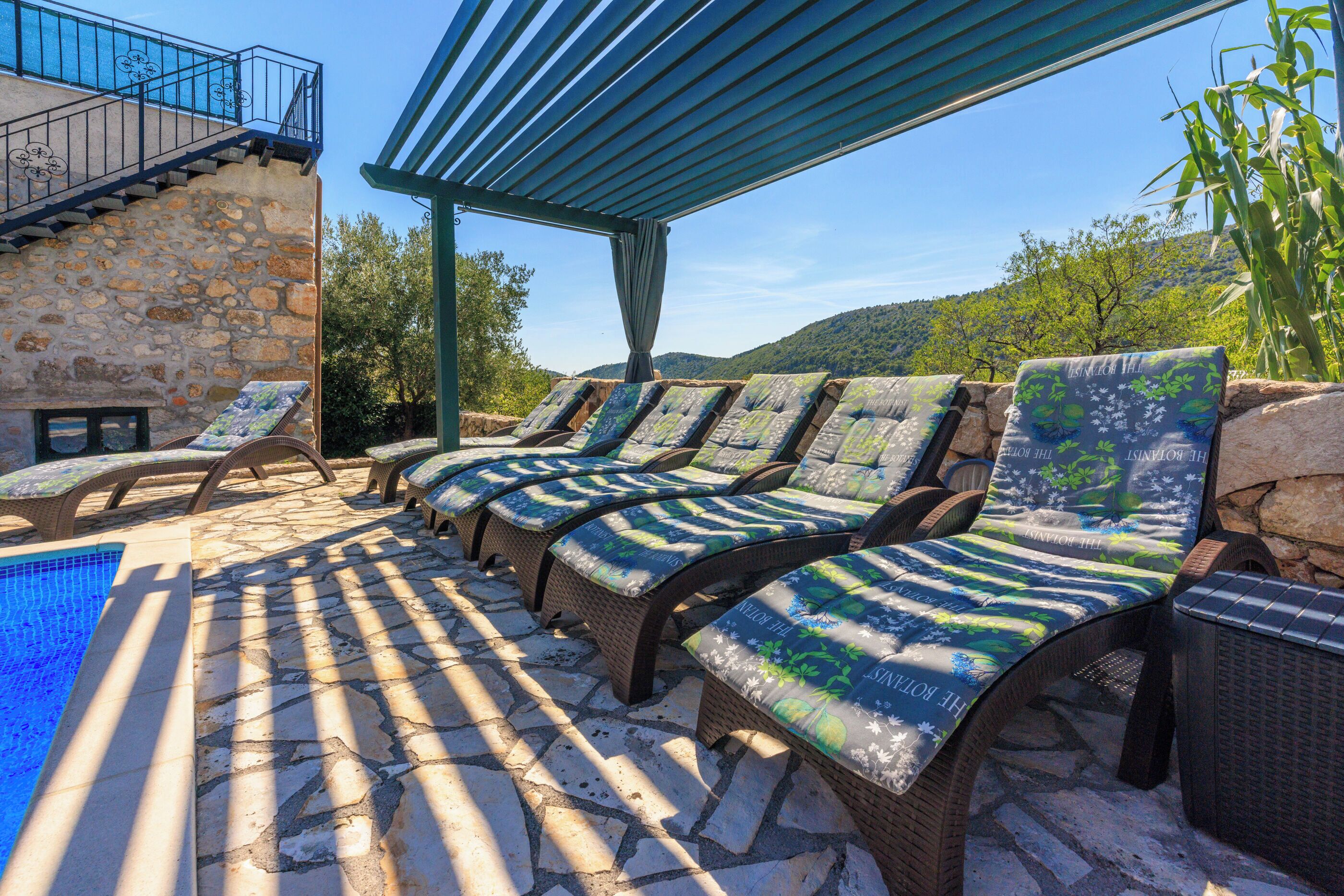 A poolside area with lounge chairs and a stone wall.