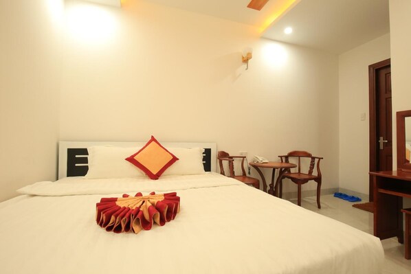 A hotel room with a neatly made bed, a small table with chairs, and a desk with a chair. - Tuyet Minh Hotel (Ho Chi Minh City)