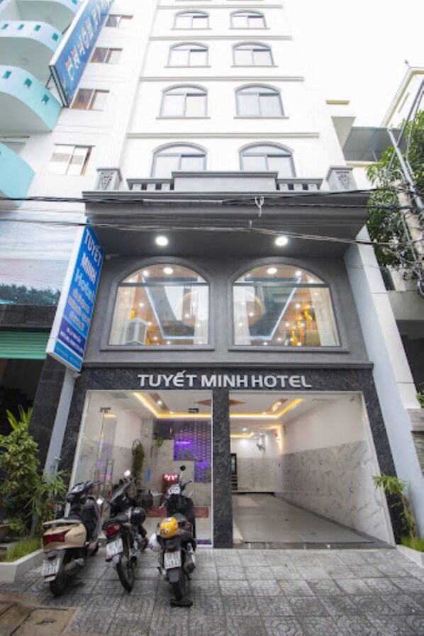 The exterior of Tuyet Minh Hotel with a clear entrance and parked motorcycles in front.