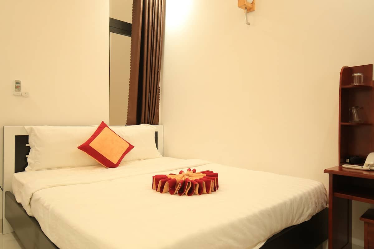 A neatly made bed with a red and beige decorative pillow and a red and beige bow.