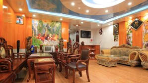 A traditional-style room with wooden furniture, a mural, and a television on the wall. - Tuyet Minh Hotel (Ho Chi Minh City)