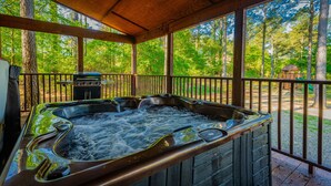 A hot tub in a covered outdoor area with a view of a forest.