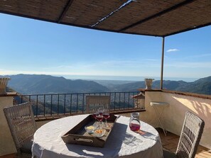 Una terraza con una mesa dispuesta para comer, con vistas a un paisaje montañoso.
