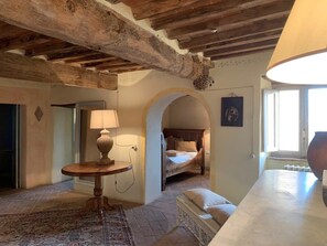 A room with a bed, a round table with a lamp, an arched doorway, and a large window. - Panorama Toscano with Splendid Sea Views, Terrace and Whirlpool (Metato)
