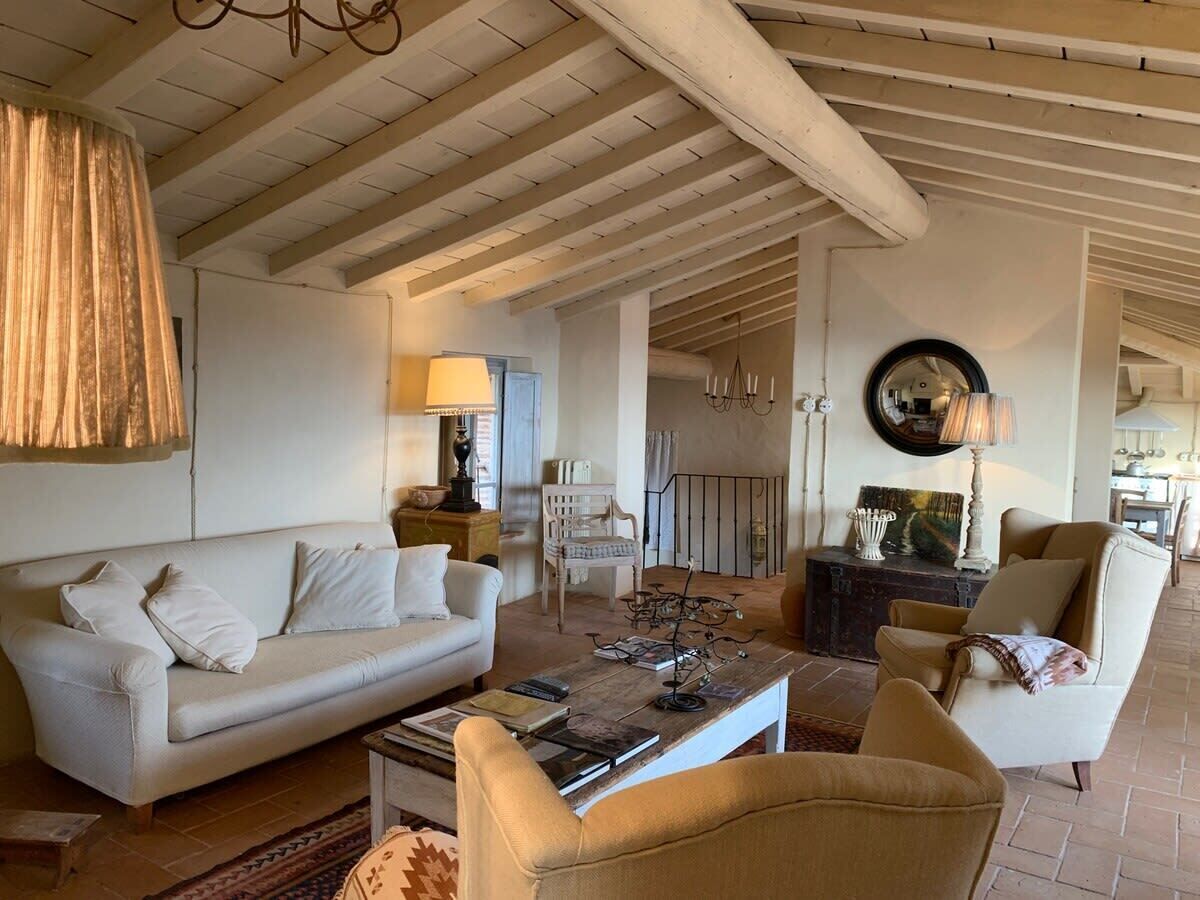 Un salon spacieux avec un plafond haut, un canapé, des fauteuils, une table basse et une cheminée.