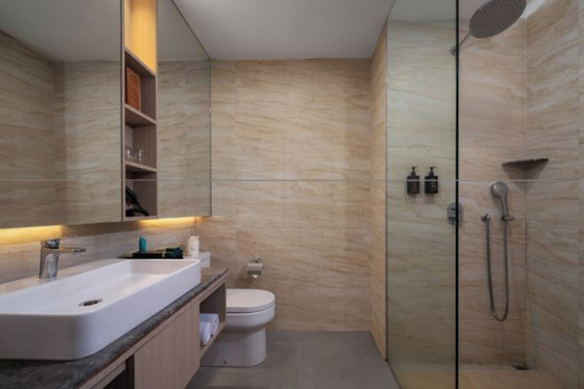 Un baño moderno con un espejo grande, un lavamanos, un inodoro y una ducha.