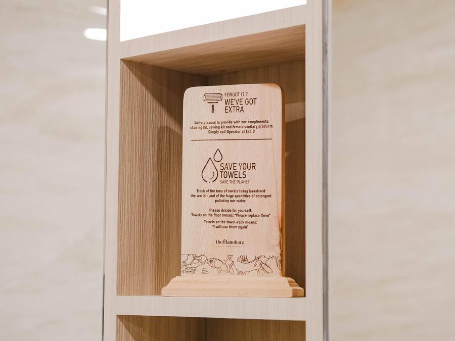 Placa de madeira com mensagem sobre poupar toalhas para proteger o planeta.