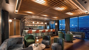A modern bar area with seating and a city view. - The Manohara Hotel Yogyakarta (Depok)