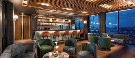 Un área de bar moderna con asientos y vistas a la ciudad.
